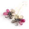 Close up of Pink, tan and black and white stone flower earrings hanging from long gold fill earwire.