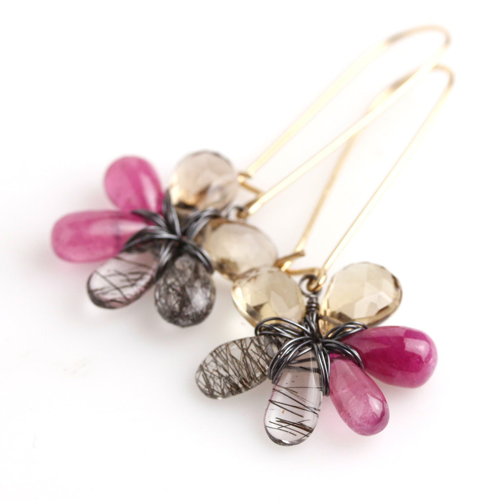 Close up of Pink, tan and black and white stone flower earrings hanging from long gold fill earwire.
