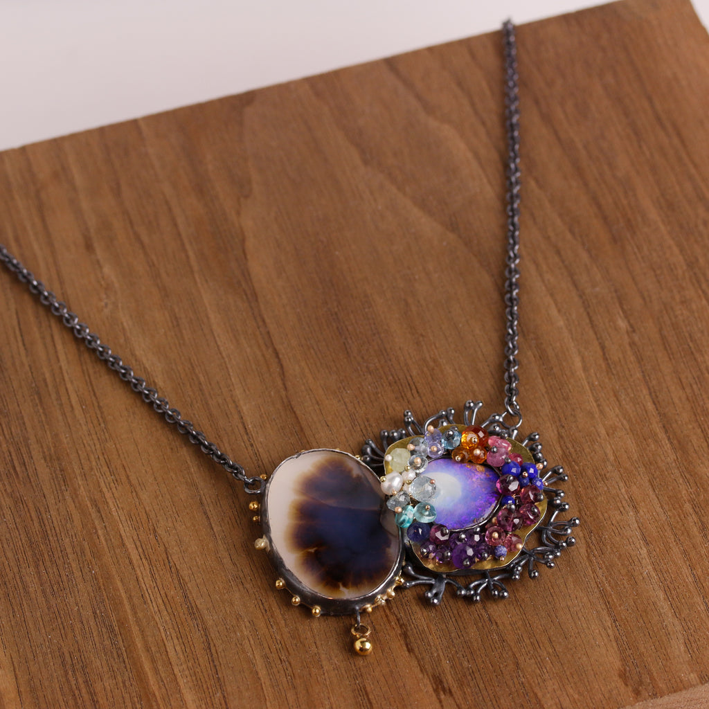 Same dendritic agate and blue opal pendant shown on a wood background.