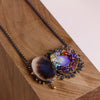 The same dendritic agate and blue opal pendant shown close up on wood.