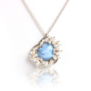 Turquoise heart pendant surrounded by clustered pearls on a silver chain close up.